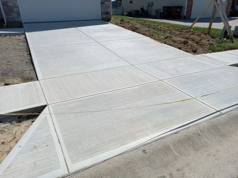 Freshly poured brushed-concrete driveway with a smooth-edged border meeting a new sidewalk